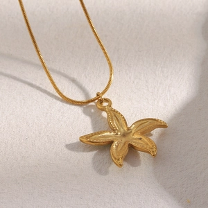 Close-up of a 18K gold plated starfish pendant on a smooth snake chain necklace