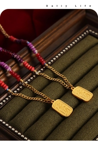 Detailed close-up of gold beaded necklaces with prosperity pendant on green velvet
