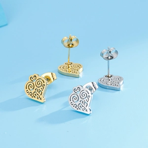 Detail of hollow heart-shaped earrings in gold and silver with intricate filigree texture