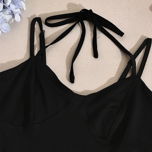 Détail du décolleté en V et des fines bretelles sur une robe noire dos nu élégante