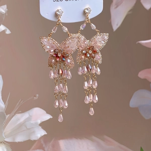Détail de boucles d'oreilles papillon roses dorées avec tiges en argent 925 pur