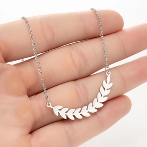 Macro detail of silver wheat leaf pendant with delicate steel chain on hand