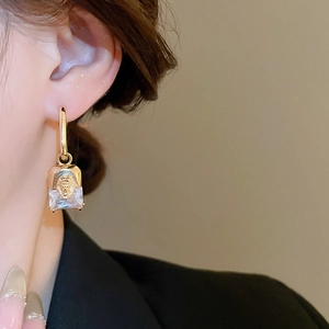 Close-up of vintage lion head earrings in gold plating with a square-cut sparkling zircon