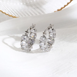 Silver luxury hoop earrings with oval-cut cubic zirconia crystals on white silk background