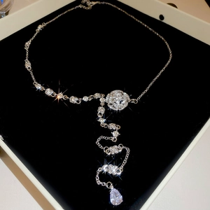 Detail of silver camellia tassel necklace with sparkling drop pendant on black velvet