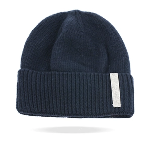 Close-up of deep blue knitted beanie with thick wool texture and a rectangular side label