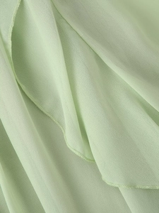Close-up of light green chiffon fabric texture and high-quality stitching on dress edge
