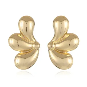 Close-up of golden geometric waterdrop earrings with a polished liquid metal finish