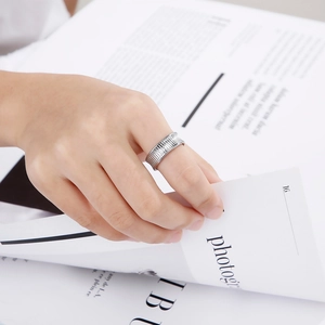 Silver wide striped stainless steel ring worn by a model holding a magazine