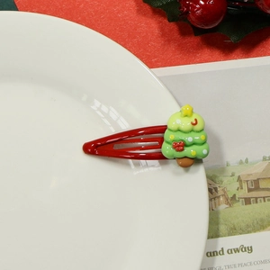 Detail of red Christmas tree hair clip with resin decorations and yellow star on white plate