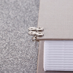Side view of silver infinity stud earrings with white zircons on a glitter background
