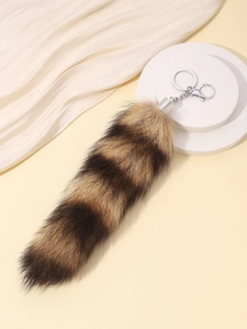 Detail of faux fur fox tail keychain with black and brown stripes and silver clasp