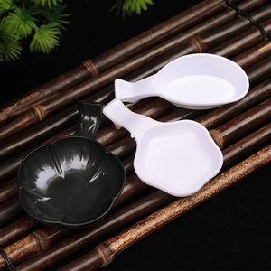 Three plastic calligraphy ink dishes in flower and oval shapes on a bamboo mat