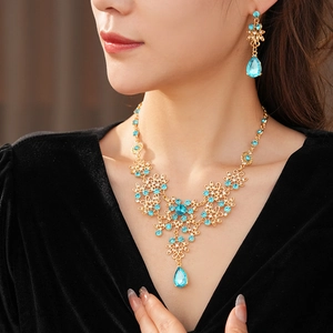 Close-up of vintage gold flower necklace and earrings set with blue teardrop crystals