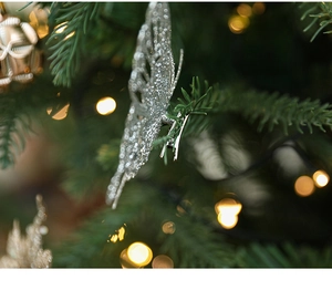 Gros plan d'un papillon pailleté argenté avec pince sur une branche de sapin de Noël