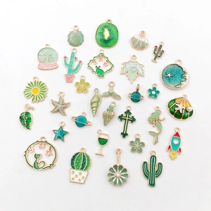 Flat lay of 30 green enamel cactus and celestial charms with gold metal edges