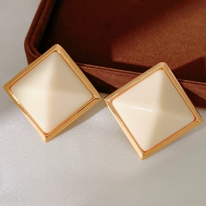 Detail view of square resin earrings with gold-plated geometric pyramid structure