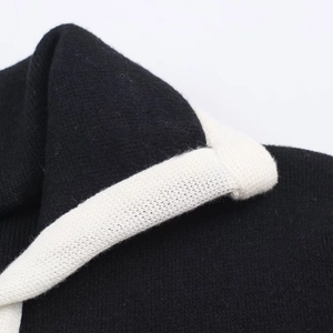 Detail von hochdichtem schwarzem Strickstoff mit weißer Kontrastkragen-Nahttextur