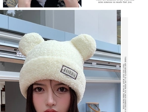 Close-up of white plush bear ear hat showing soft fleece texture and logo detail