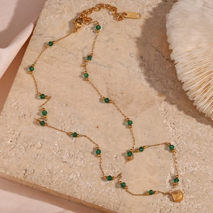 Detail of K18 engraved clasp on gold chain with green beads and shell pendant