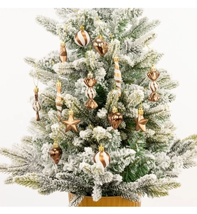 Close-up of bronze and white glitter Christmas ornaments on a snowy pine branch