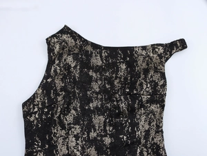 Detail of black slim dress with metallic gold foil texture and asymmetrical shoulder cut