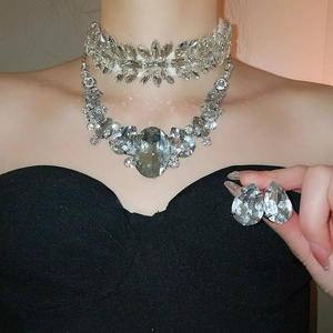 Detail of luxury teardrop crystal necklace and earring set on model for elegant style