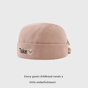 Détail du bonnet bébé en velours côtelé rose avec ours brodé et lettrage Take