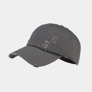 Close-up of distressed ripped details on a dark grey vintage washed cotton baseball cap