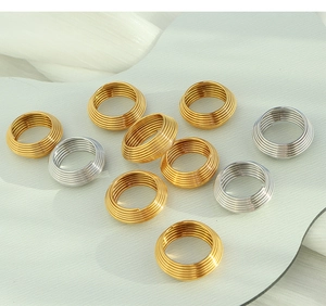 Detail view of multi-layer spiral 18K gold and silver plated geometric rings on white decor