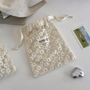 Close-up of white mesh lace storage bag with delicate daisy floral embroidery and drawstring