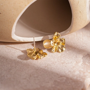 Detailaufnahme goldener Blumenohrringe mit weißen Harz-Opalen und Silberstiften im Fokus