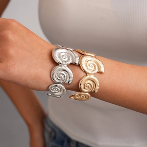 Detail of spiral shell texture bangles in gold and silver finish for beach style