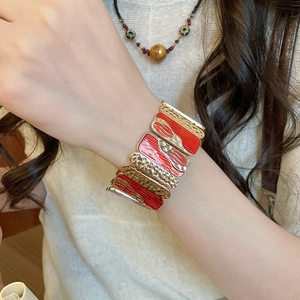 Close-up of red enamel and hammered gold wide cuff bracelet worn on female wrist