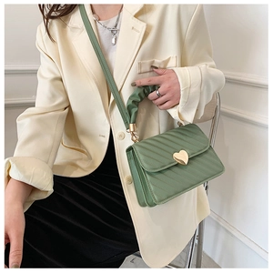 Green PU leather handbag featuring diagonal stitching and a gold heart-shaped metal clasp