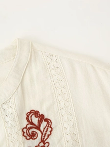 Detail of floral embroidery and lace hollow stitching on a beige cotton linen blouse