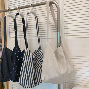 Retro canvas tote bags in solid colors, stripes, and polka dots hanging on a metal rack