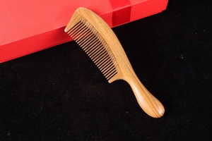 Macro shot of natural sandalwood comb with fine teeth on a dark textured background