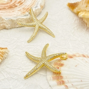 Detail of a golden starfish pendant with micro-pave zircons on a natural seashell