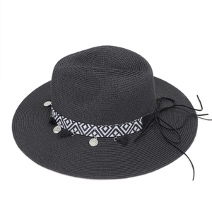 Detail of wide brim straw hat with ethnic tassel trim and silver coin charms