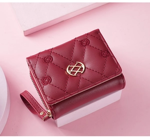 Macro detail of wine red embroidered leather wallet with golden logo on a pedestal