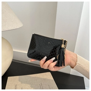 Close-up of black crocodile pattern coin purse with gold chain and black tassel detail