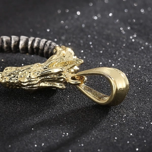 Macro shot of a golden dragon head pendant with detailed scales on black textured surface