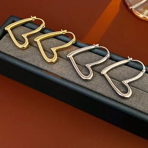 Détail de boucles d'oreilles en forme de cœur dorées et argentées dans un écrin à bijoux