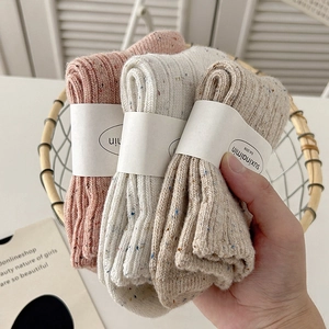 Three pairs of colorful speckled wool socks in pink, white, and coffee colors