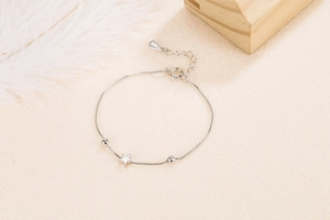 Detailed close-up of S925 sterling silver star pendant and beaded chain on a beige surface