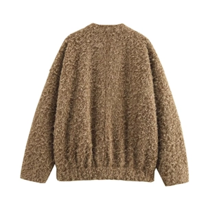 Gros plan sur la veste en maille bouclée marron montrant la texture douce effet laine