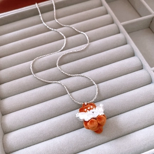 Close-up of a brown flocked bear necklace with silver wings on a velvet jewelry tray