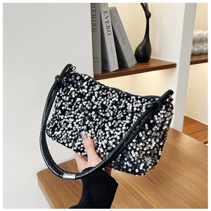 Detail shot of silver sequins on baguette bag with black leather shoulder strap