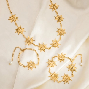 Golden stainless steel sun pendant jewelry set with necklace and bracelets on silk
